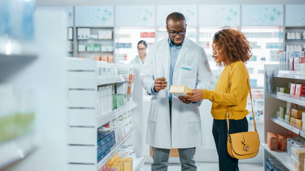 Pharmacy: Professional Black Pharmacist Helping Beautiful Latin Female Customer with Medicine Recommendation, Advice, Talking. Drugstore with Full of Drugs, Pills, Health Care, Beauty Product Packages|||