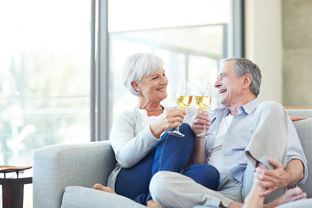 Shot of a senior couple drinking champagne while sitting on the sofa at home|||