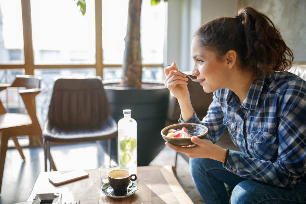 Woman eating cereals with yogurt for breakfast|||