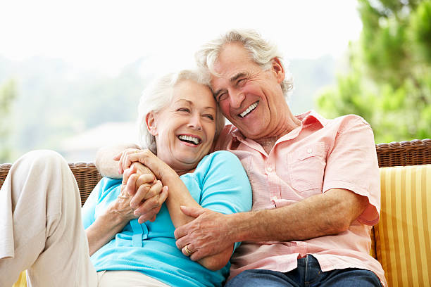 Senior Couple Sitting On Outdoor Seat Together Laughing|Romantic Senior Couple Hugging On Beach Smiling To Camera|||